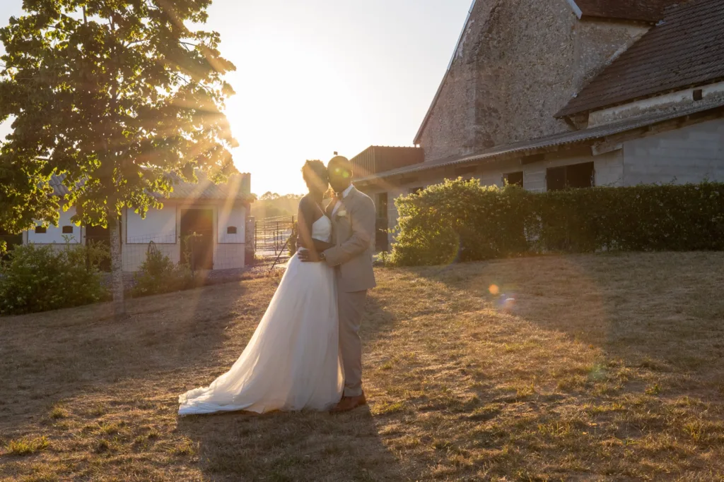 Baiser des mariés en contre-jour devant la ferme de L'Étable de Véronge