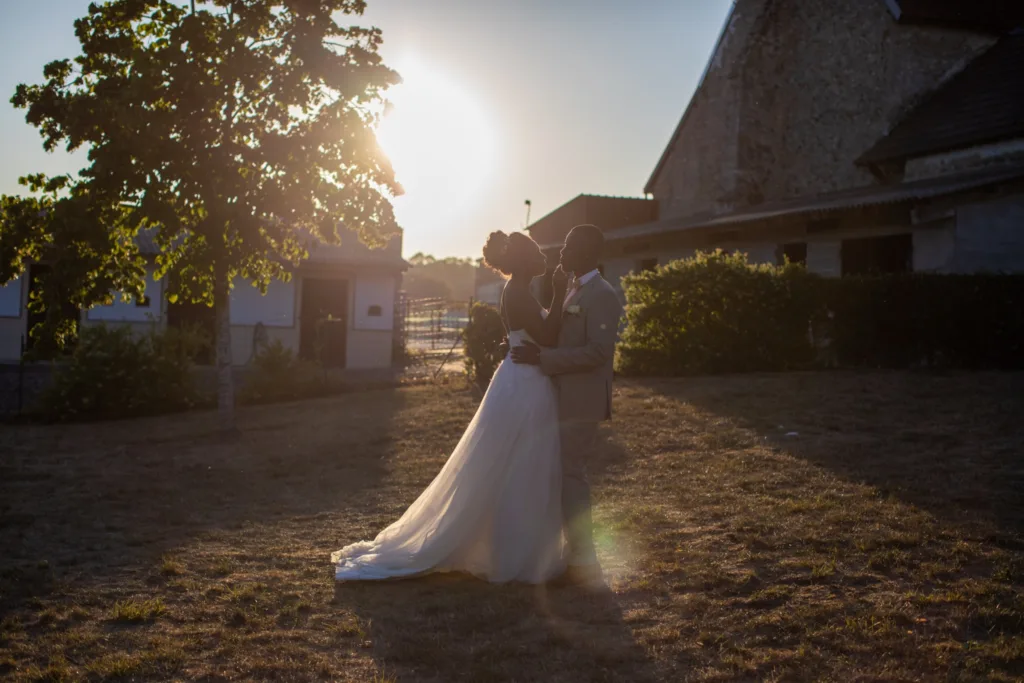 Silhouette des mariés enlacés dans la lumière du soir, cour de la ferme briarde