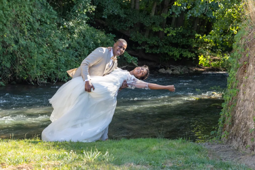 Le marié fait basculer la mariée au bord d'une rivière