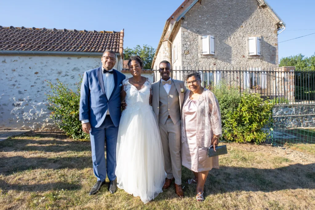 Photo de famille des mariés devant les bâtiments en pierre de la ferme