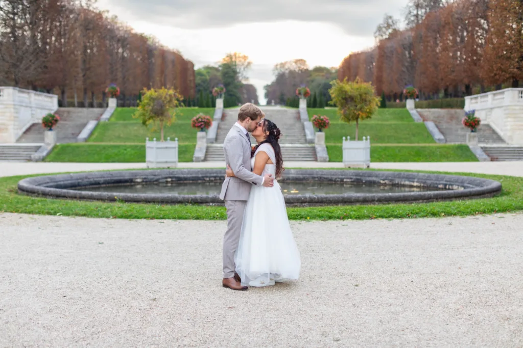 Baiser des mariés devant un bassin et les perspectives du parc de Saint-Cloud