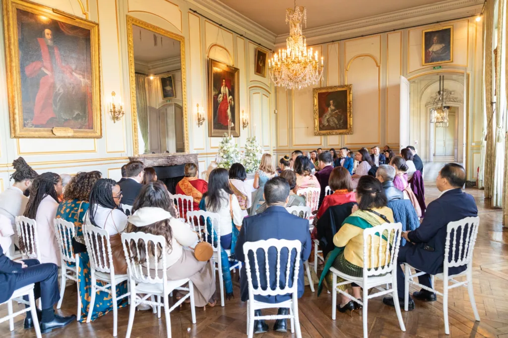 Cérémonie laotienne dans un salon du Château de Champlâtreux, invités réunis sous le lustre