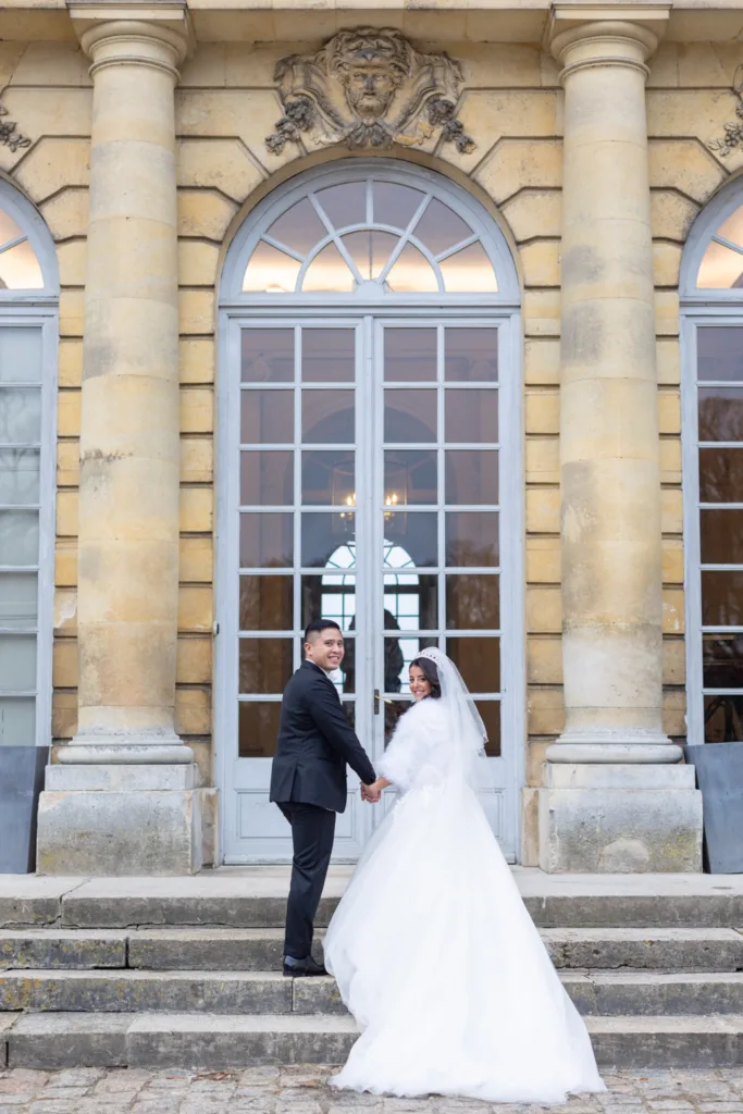Photo de couple sur le perron du Château de Champlâtreux, robe de mariée et porte-fenêtre cintrée