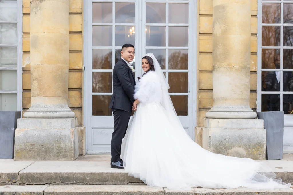 Les mariés devant les colonnes du perron du Château de Champlâtreux en hiver