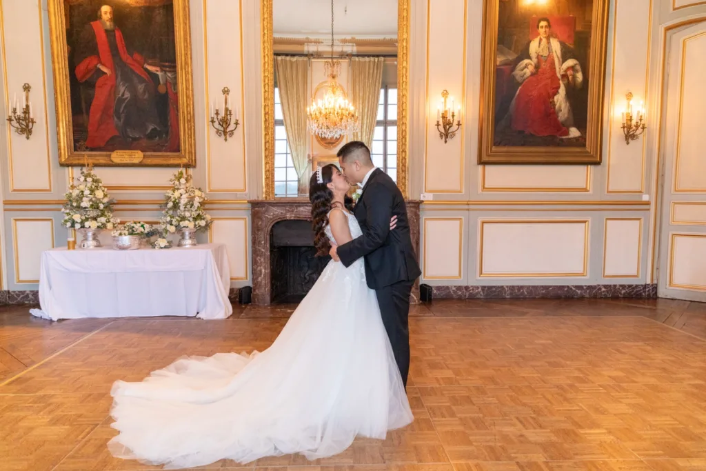 Baiser des mariés dans le grand salon du Château de Champlâtreux, cheminée, portraits et lustre en cristal