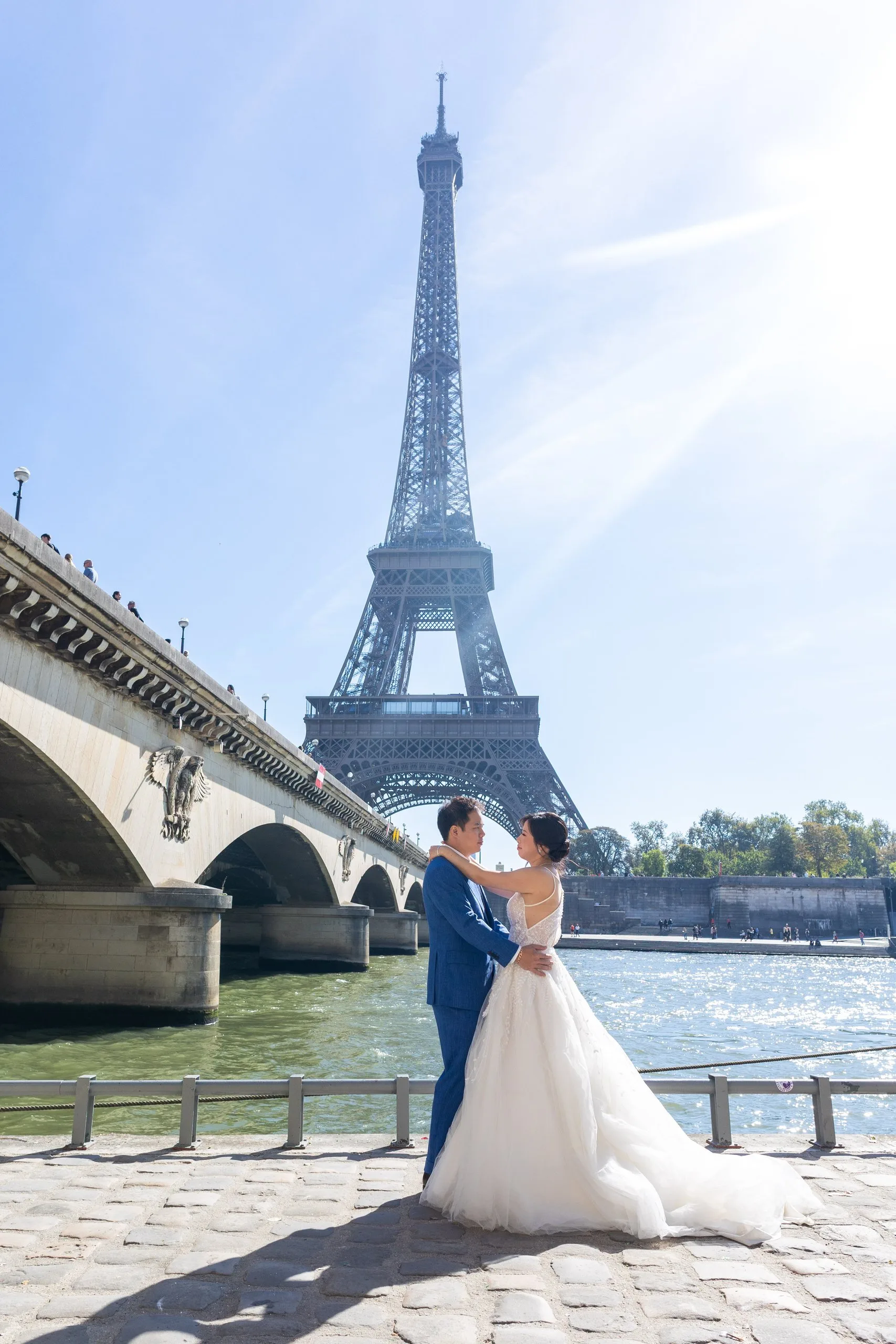 Mariés enlacés au bord de la Seine avec la tour Eiffel en arrière-plan