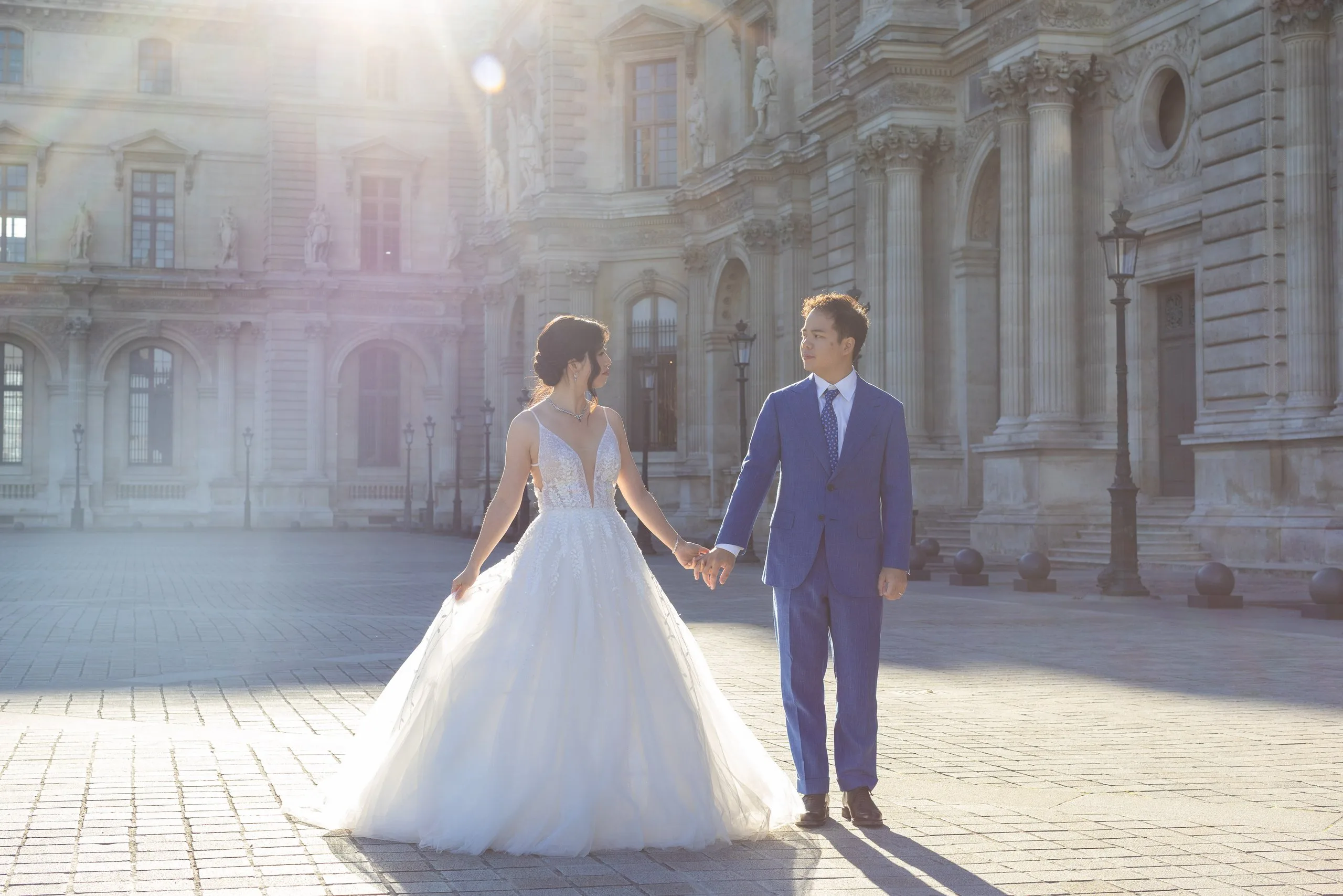 Mariés main dans la main à contre-jour dans une cour du Louvre