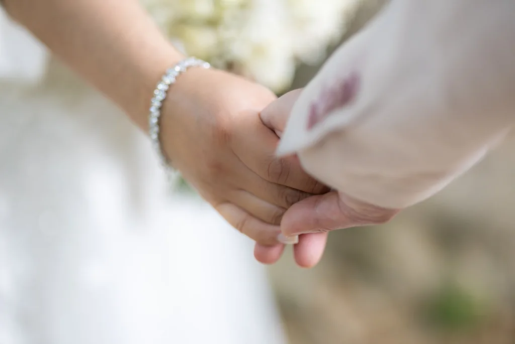Gros plan sur les mains enlacées de Monita et Jérémy, bracelet de la mariée