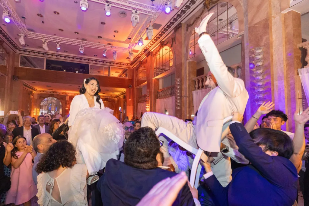 Monita et Jérémy soulevés sur des chaises par leurs invités pendant la hora aux Salons Hoche