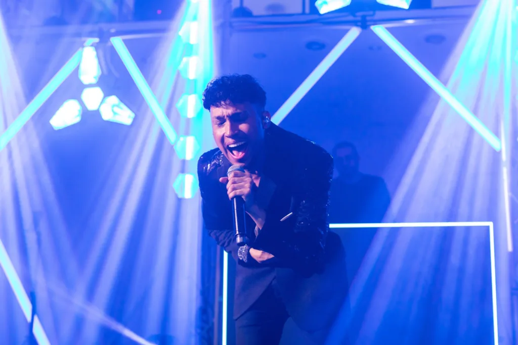 Chanteur sur scène sous les faisceaux de lumière bleue pendant la soirée de mariage aux Salons Hoche