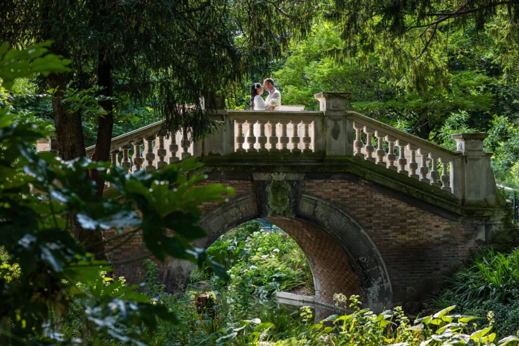 Monita et Jérémy sur un pont de pierre entouré de verdure lors de leur séance photo de couple à Paris