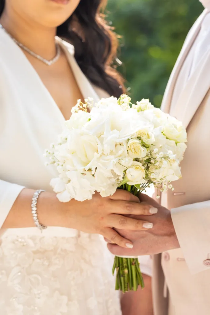 Détail du bouquet de roses blanches de la mariée et des mains des mariés